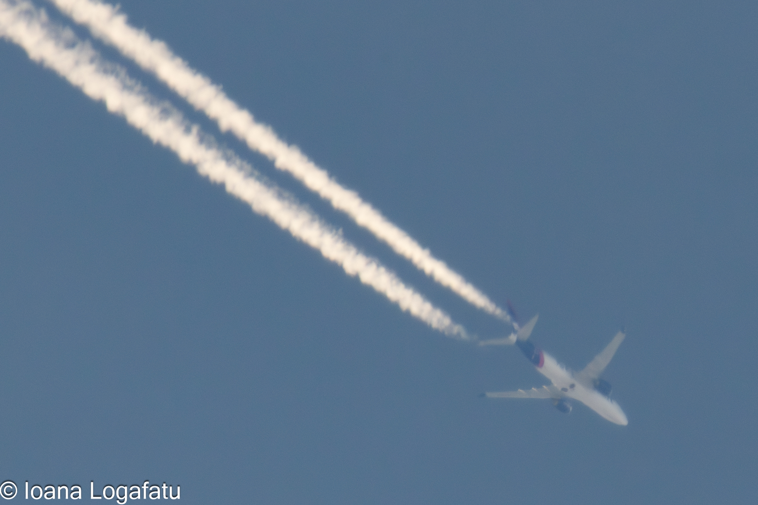 Jet streams crisscrossing a clear blue sky above